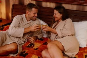 un hombre y una mujer sentados en una cama con bebidas en Thermae Grimbergen Hotel, en Grimbergen