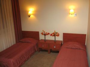 a hotel room with two beds and flowers on a table at Zajazd Michałowo in Michałowo