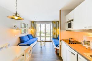 un salon avec des canapés bleus et une cuisine dans l'établissement Le Cap Glénan - maeva Home - 2 Pièces 5 Personnes Confort MAE-5648, à Bénodet 5 autres photos
