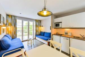 un salon avec un canapé bleu et une cuisine dans l'établissement Le Cap Glénan - maeva Home - 2 Pièces 5 Personnes Confort MAE-5648, à Bénodet