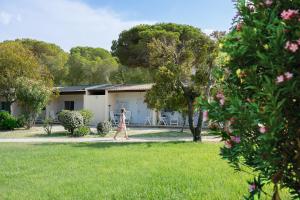 une femme marchant dans une cour devant une maison dans l'établissement Feriendorf zum störrischen Esel, à Calvi