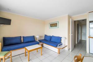 ein Wohnzimmer mit blauen Sofas und einem Tisch in der Unterkunft Résidence le Hameau de Cap Esterel - maeva Home - Appartement 2 Pièces 7 Pe 20 in Saint-Raphaël