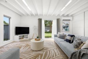 sala de estar con sofá y TV en Charming 5-Bed Coastal Escape in Maroochydore en Maroochydore
