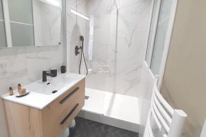 biała łazienka z prysznicem i umywalką w obiekcie Promo Easy Clés- Flat city center with Parking w Biarritz