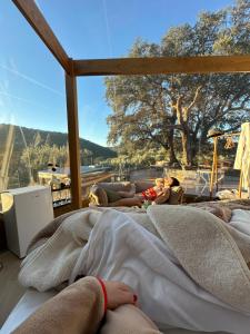 two people laying on beds in a room with a large window at SUITE 19 BUBBLE BY CORTIJO COLOMO in Almedinilla