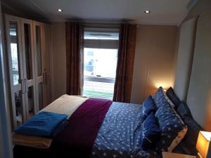 Un dormitorio con una cama con almohadas azules y una ventana en 19 Park Views Just outside Penrith for Holidays and Short Breaks please no commercial vans thankyou en High Hesket