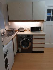 a kitchen with a washing machine and a microwave at Perry House in Nottingham