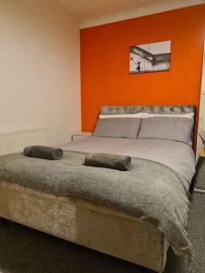 a bedroom with a bed with an orange wall at Perry House in Nottingham