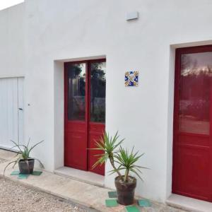 dos puertas rojas en un edificio blanco con dos plantas en Al Gelso Bianco appartamento, en Castrignano del Capo