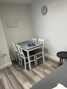 a dining room table with chairs and a clock on the wall at The Cosy Nook in Redruth