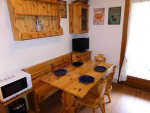 mesa de comedor de madera con sillas y microondas en Résidence L'enclave - Studio pour 4 Personnes 53 en Les Contamines-Montjoie