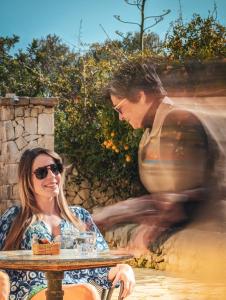 una mujer sentada en una mesa frente a una fuente en Hotel La Corte Del Sole, en Noto