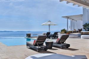 a patio with chairs and a swimming pool with the ocean at Exquisite Mykonos Villa - Villa Lakima - 6 Bedroom - Infinity Pool - Panoramic Sea And Sunset View - Pool Bar in Fanari