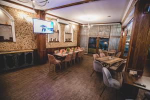 a dining room with tables and chairs and a television at Rodopi Hotel in Haskovo