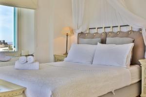 a bedroom with a large white bed with a window at Exquisite Mykonos Villa - Villa Lakima - 6 Bedroom - Infinity Pool - Panoramic Sea And Sunset View - Pool Bar in Fanari