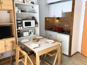 a small kitchen with a table with chairs and a microwave at Résidence Borgia - Studio pour 4 Personnes 67 in Les Contamines-Montjoie