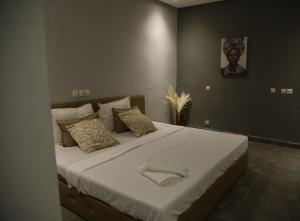 a bedroom with a large bed with white sheets and pillows at The Shelter Abidjan in Abidjan