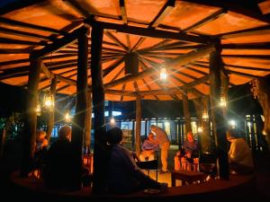 un grupo de personas sentadas en una tienda por la noche en Emerald Tiger Retreat, en Tāla