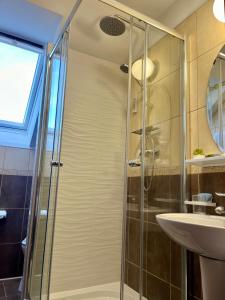 a shower with a glass door next to a sink at Cetățuia - Ultra-Central Râșnov Stay - Parking and Nature Close to Bran, Dino Parc and More in Râşnov