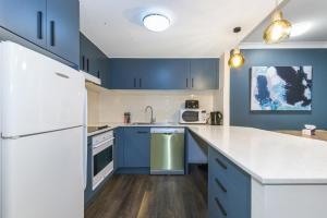 a kitchen with blue cabinets and a white refrigerator at Hotel styling entire one bedroom in Sydney