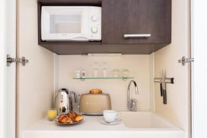 a small kitchen with a sink and a microwave at Kipling Manotel in Geneva