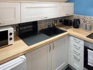 a kitchen with white cabinets and a sink at High View in Saint Breward