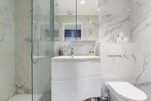 ein weißes Bad mit einem Waschbecken und einer Dusche in der Unterkunft Auguste Comte - Studio tout équipé - Cœur de Lyon in Lyon