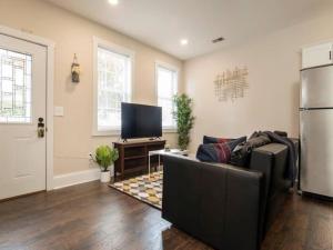 a living room with a couch and a tv at Spacious 3BR House with Backyard in NULU CozySuites in Louisville