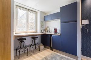 eine Küche mit blauen Schränken und 2 Barhockern in der Unterkunft Auguste Comte - Studio tout équipé - Cœur de Lyon in Lyon