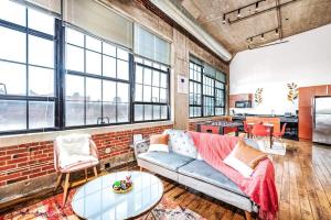 a living room with a couch and a brick wall at 2BR Architect's STUNNING loft by CozySuites in Saint Louis