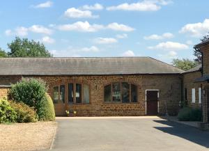 a brick house with a driveway in front of it at Beautiful 2 Bedroom Barn in Towcester Northants in Litchborough