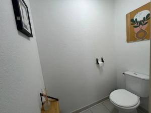 a white bathroom with a toilet and a picture on the wall at ELSA / Appartement P3 + Parking in Nîmes