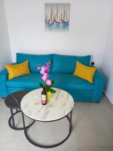 a living room with a blue couch and a table with flowers at KaVros Cozy Apartment in Kavros