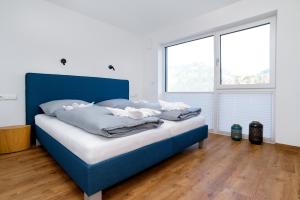a blue bed in a room with two windows at Berg Fux - Ferienwohnung Francis der Esel in Sonthofen