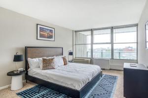 a bedroom with a large bed and some windows at TWO 800 Tower CozySuites w skypool lounge 10FLR in Louisville