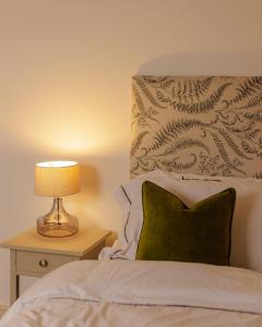 a bed with a pillow and a lamp on a night stand at The Dashwood in Kirtlington