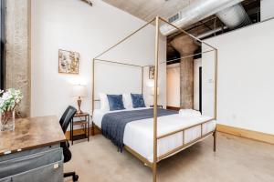 TWO Stunning Adler Loft by CozySuites في سانت لويس: غرفة نوم مع سرير المظلة ومكتب