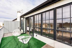a balcony with two chairs and green flooring at TWO Stunning Adler Loft by CozySuites in Saint Louis