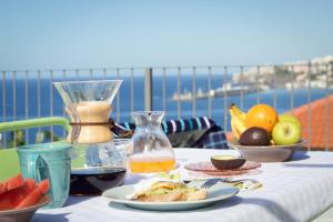 - une table avec une assiette de nourriture et une carafe de jus dans l'établissement Irlandas Villa Funchal Seaside Villas, à Funchal