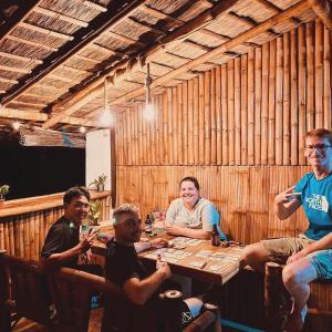 um grupo de pessoas sentadas em torno de uma mesa em um restaurante em Sunnyside Moalboal Guest house - 써니사이드 모알보알 게스트하우스 em Moalboal