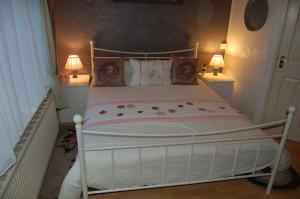 a white bed in a room with two lamps at The Willows in Tintagel