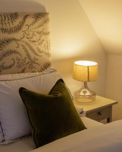 a bedroom with a bed with a pillow and a lamp at The Dashwood in Kirtlington