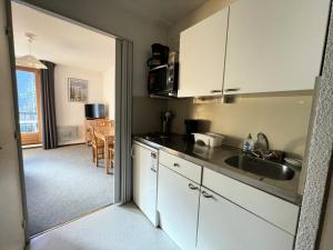 a kitchen with white cabinets and a sink at Résidence Pollux - Studio pour 4 Personnes 15 in Flaine
