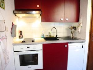een rode en witte keuken met een wastafel en een fornuis bij Résidence Casino - 2 Pièces pour 5 Personnes 304 in Barèges