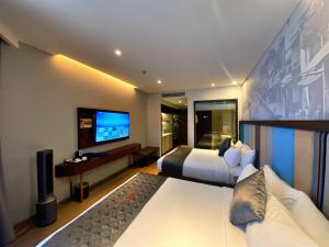 um quarto de hotel com uma cama e uma televisão em Apec Mandala Mũi Né - Khách Sạn Nghĩ Dưỡng Luxury Limited em Ấp Thiẹn Ái