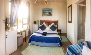 a bedroom with a blue and white bed and a window at Bayview Guest House in Amanzimtoti