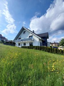 una casa blanca en una colina con un campo de hierba en Haus Panoramasicht, en Höchenschwand