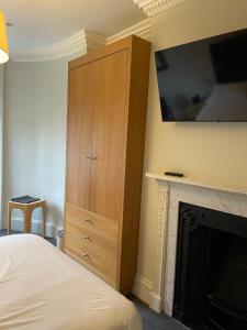 ロンドンにあるケニントン B＆Bの暖炉と壁にテレビが備わるベッドルーム1室