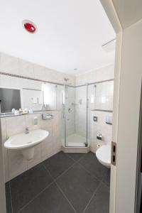 biała łazienka z umywalką i prysznicem w obiekcie Bernstein Schlosshotel Ballenstedt w mieście Ballenstedt