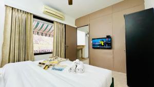 a hotel room with a bed with towels and a tv at BluO Vasant Vihar PVR - Terrace Garden, Lift in New Delhi